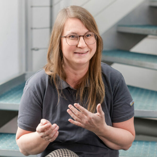 Kollegiales Gespräch zwischen Mitarbeitenden auf einer Treppe im Büro.