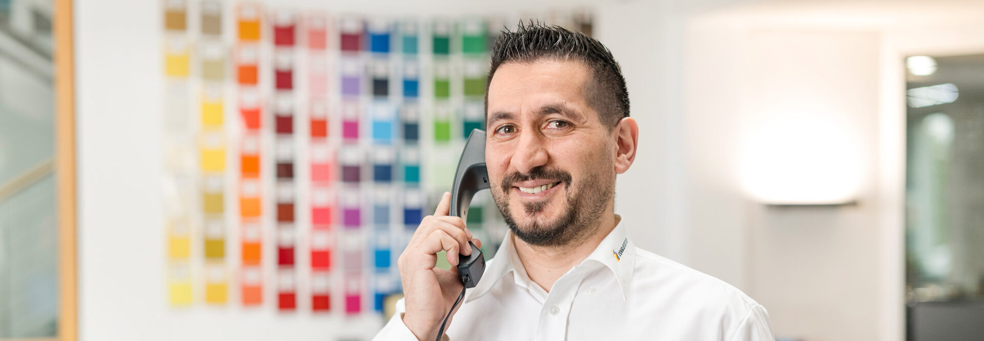 Mitarbeiter im Kundenservice hat Kontakt mit Kunden im Büro mit Farbmustern im Hintergrund.