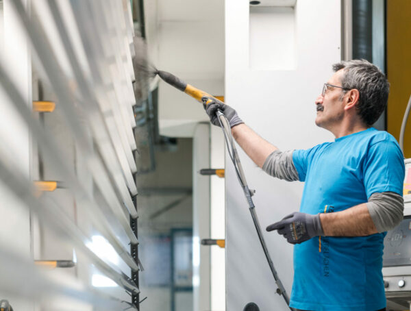 Facharbeiter trägt Pulverbeschichtung auf Aluminiumlamellen auf.