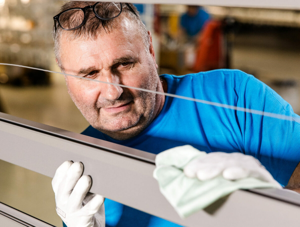 Mitarbeiter von Längle Oberflächen überprüft und reinigt ein beschichtetes Aluminiumprofil für höchste Qualitätsstandards.
