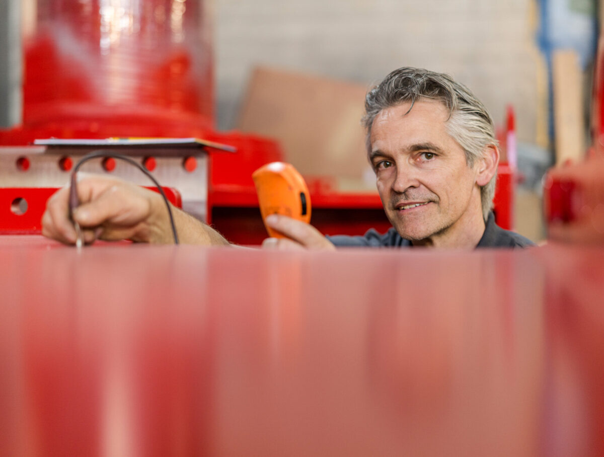 Fachmann prüft mit Messgerät die Schichtdicke einer Nasslackierung.