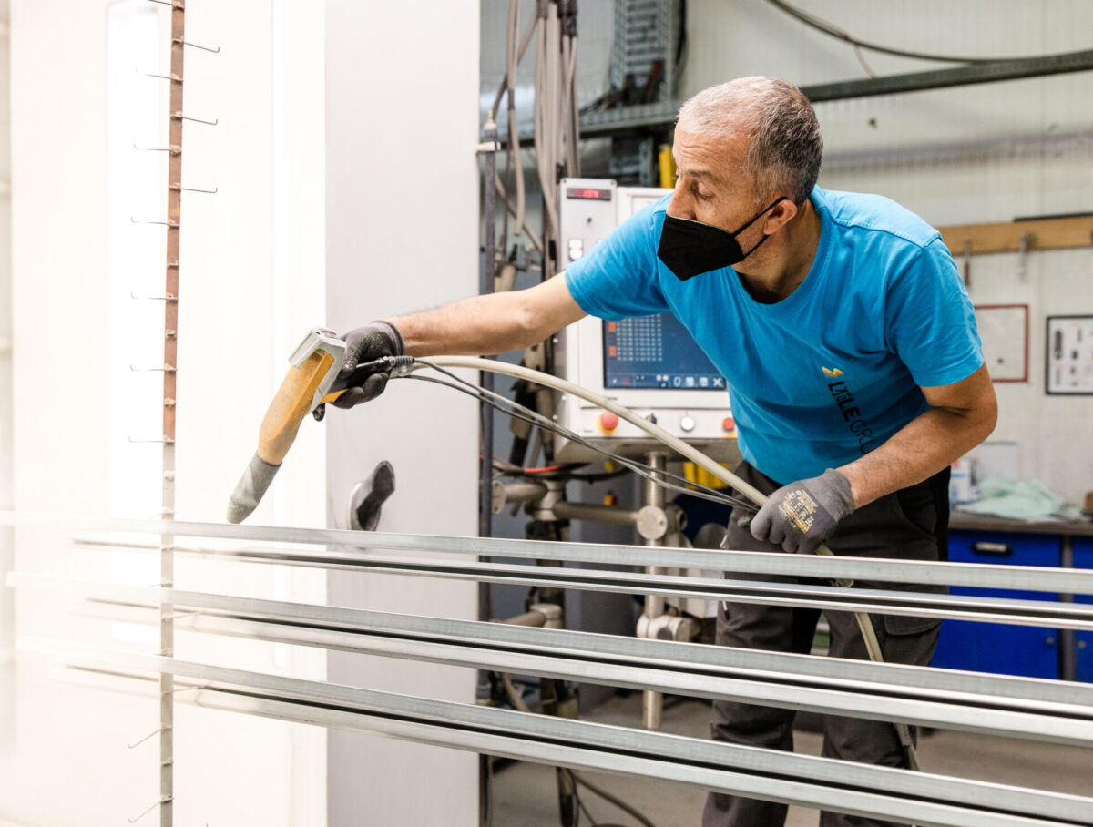 Mitarbeiter von Längle Oberflächen beim präzisen Auftragen von Pulverlack auf Metallprofile.