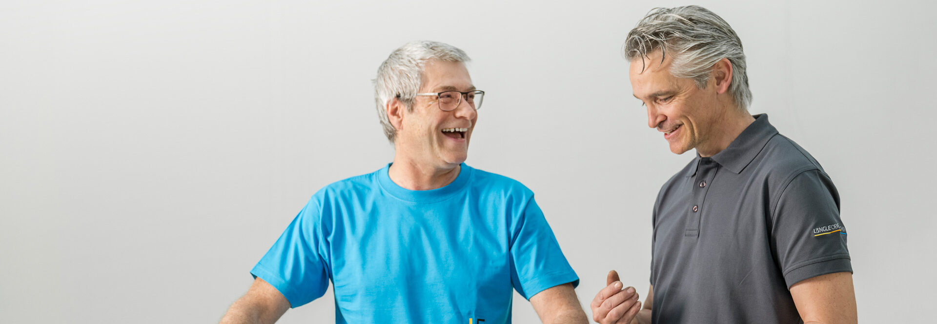 Zwei Mitarbeiter stehen an einem Tresen und führen ein freundliches Gespräch.