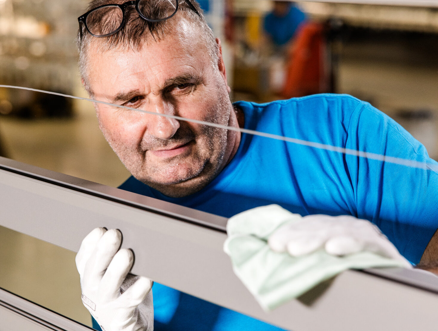 Mitarbeiter von Längle Oberflächen überprüft und reinigt ein beschichtetes Aluminiumprofil für höchste Qualitätsstandards.